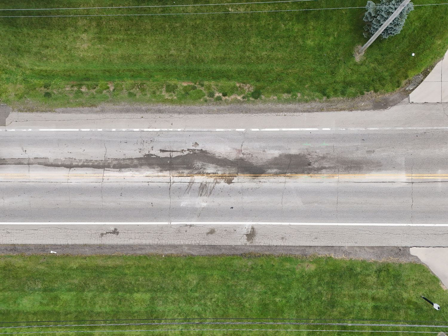 Top-down view of gouge marks and fluid trails across a roadway centerline