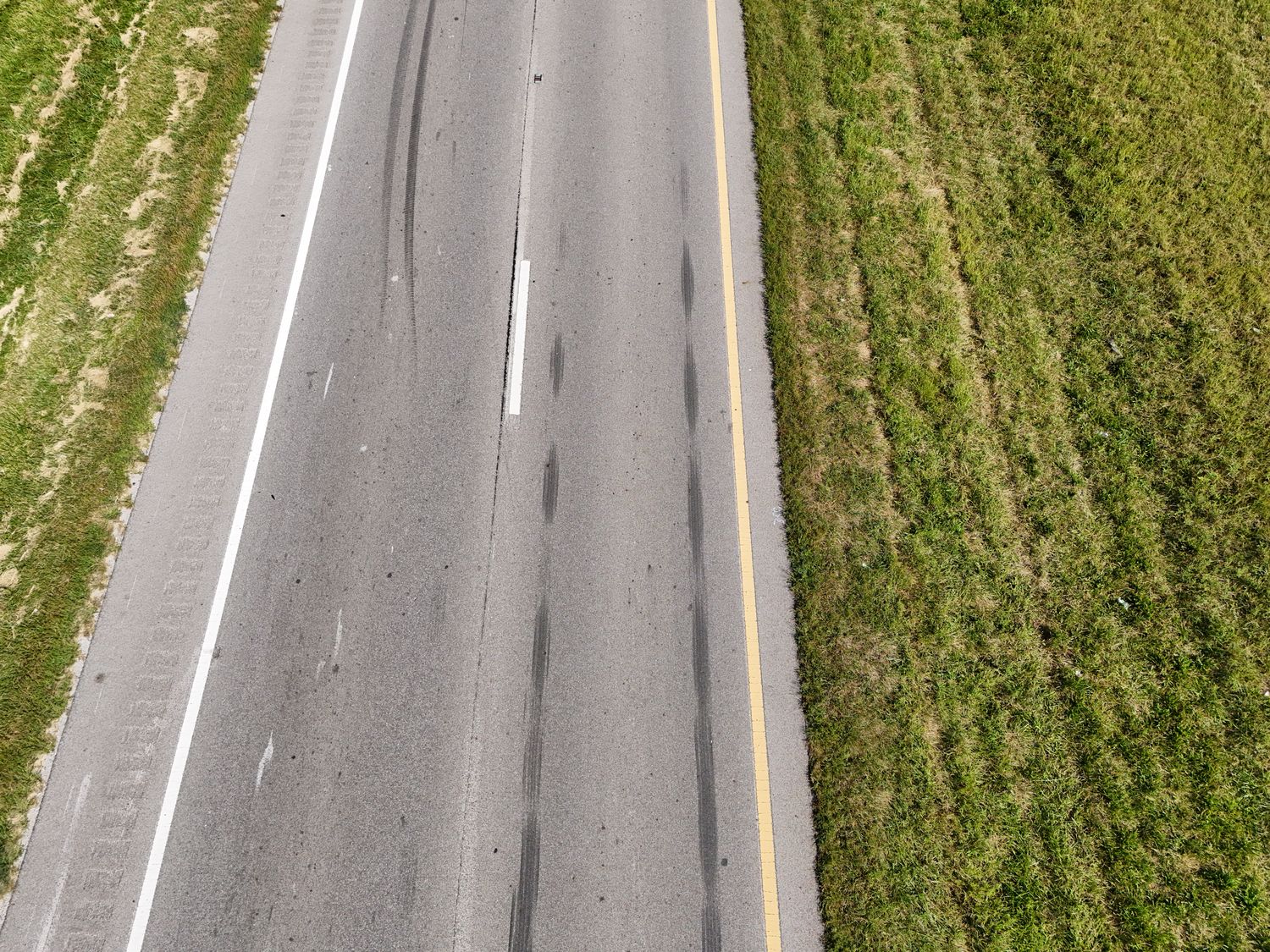 Top-down view of dark tire marks running along the travel lanes of a road