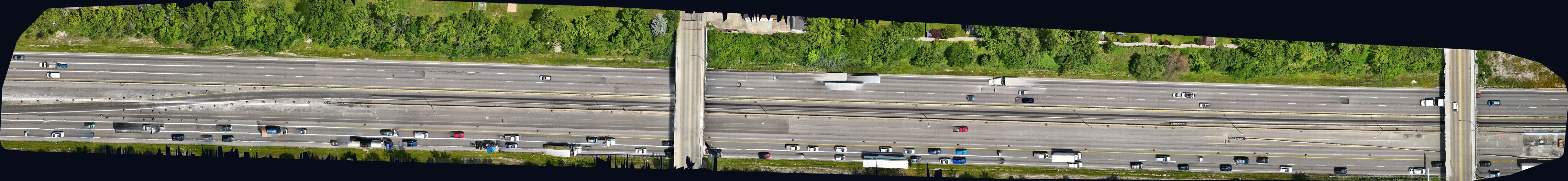 Wide top-down orthomosaic of a multi-lane highway corridor with overpasses and traffic